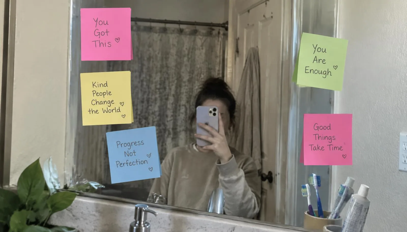 Colorful sticky notes with encouraging handwritten messages stuck around a bathroom mirror